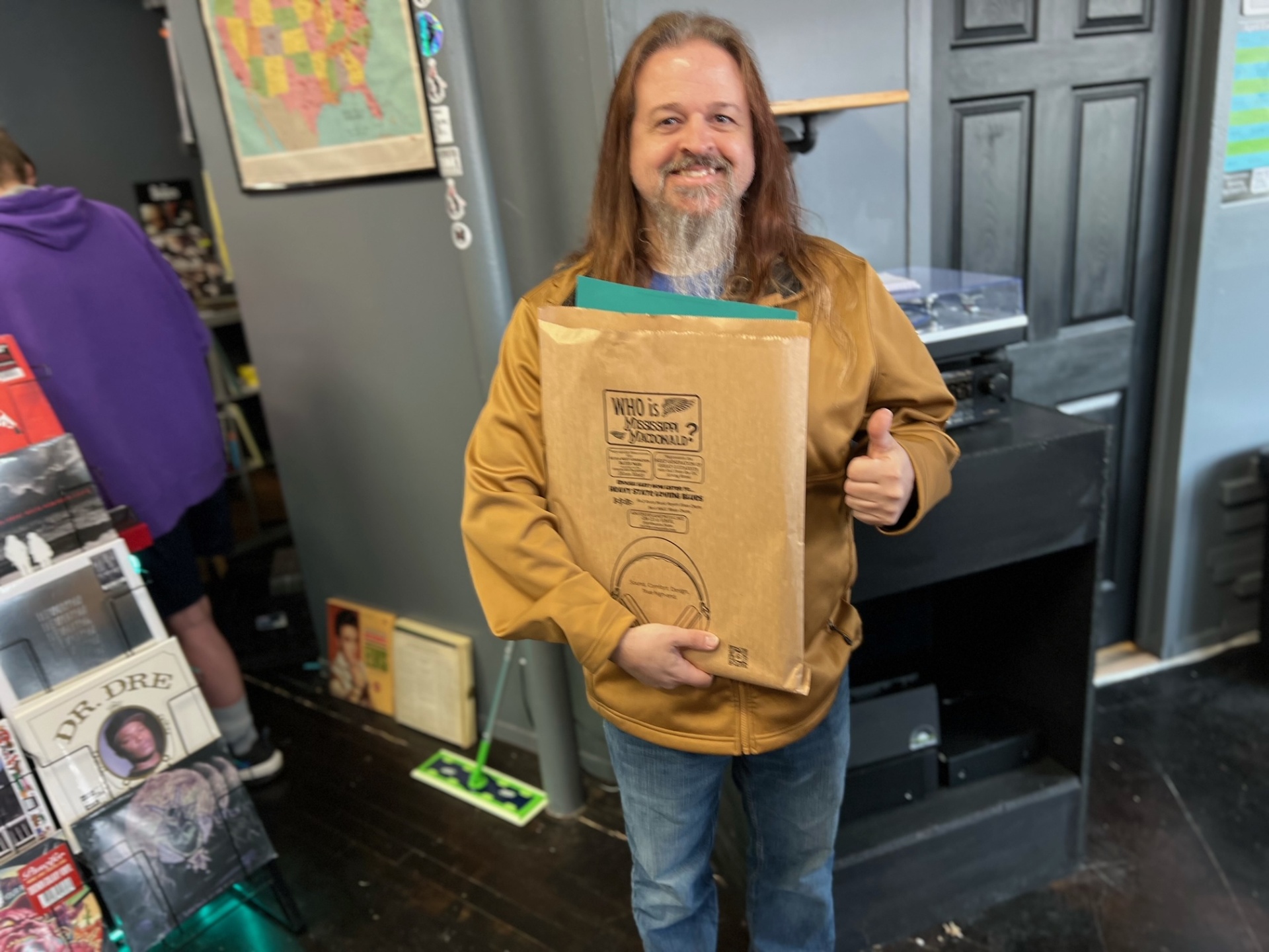 A record store customer carrying a printed campaign bag through the shop